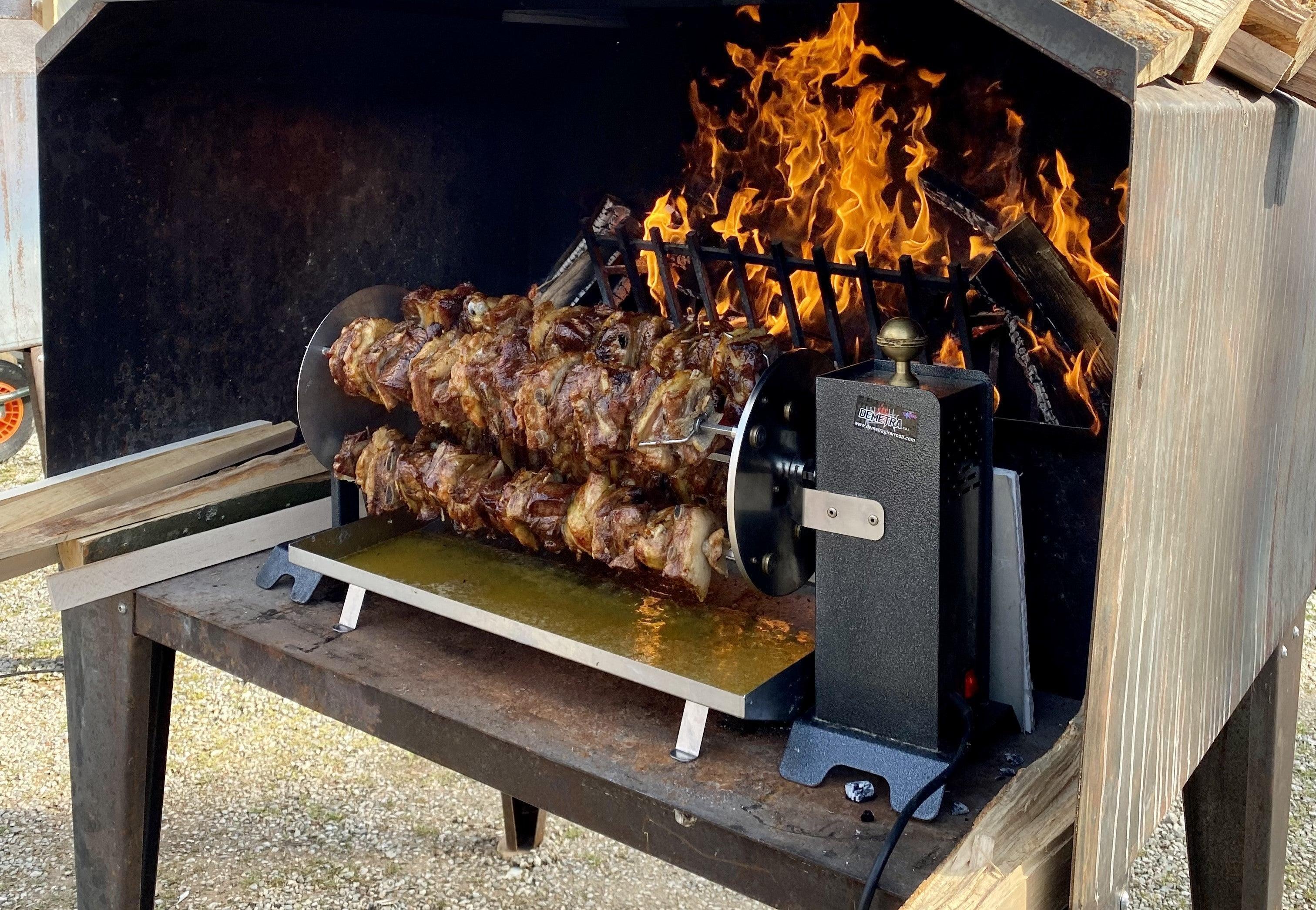 Girarrosto in acciaio inox con carne arrostita su fuoco vivo per barbecue all'aperto