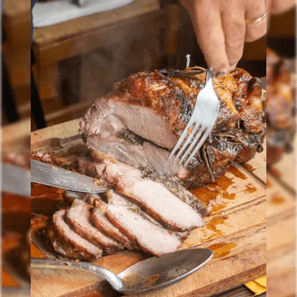 Arrosto di maiale appena tagliato su tagliere in legno, pronto per essere servito
