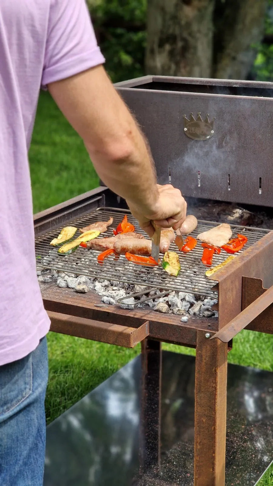 Barbecue a carbone con griglia in acciaio, ideale per grigliare carne e verdure all'aperto.