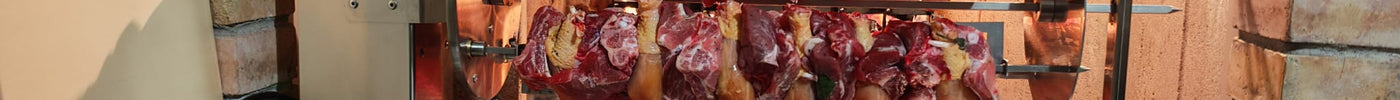 Girarrosto in acciaio inox con carne e pollo su spiedi, pronto per barbecue all'aperto.