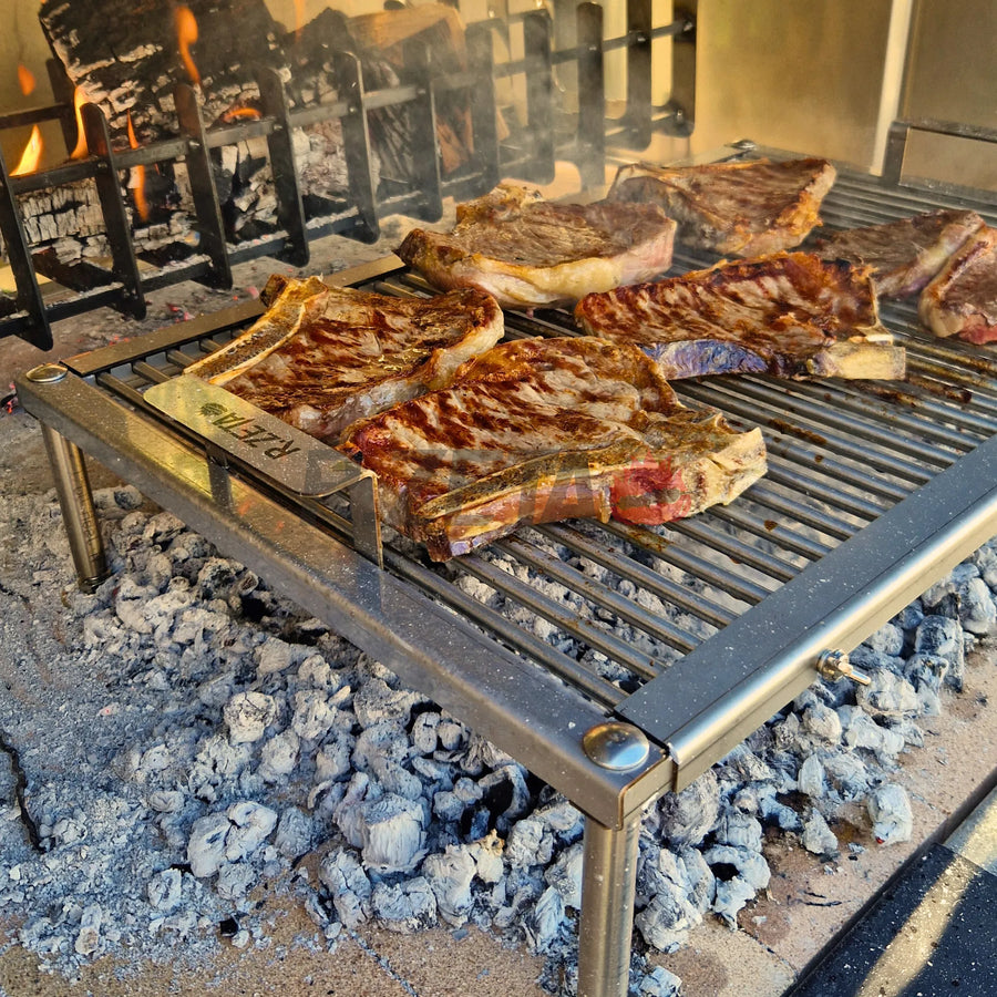 Bistecca alla griglia su griglia in acciaio inox con braci ardenti, ideale per barbecue professionale.