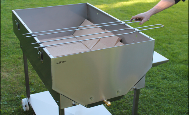 Girarrosto in acciaio inox RZeta con griglia regolabile, ideale per barbecue all'aperto su erba.